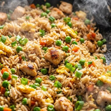Sizzling chicken fried rice in wok with golden chicken, scrambled eggs, green onions, and savory soy sauce