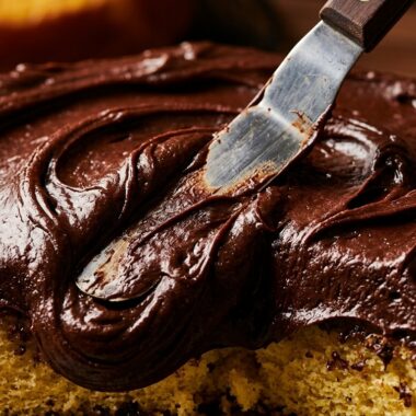 Ultra close up macro of rich glossy old fashioned chocolate fudge frosting swirled onto yellow cake