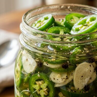 Ultra close up of crisp sliced pickled jalapenos with garlic in a mason jar