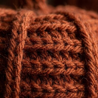 Ultra close up macro texture of rustic ribbed crochet pumpkin in terracotta burnt orange wool yarn